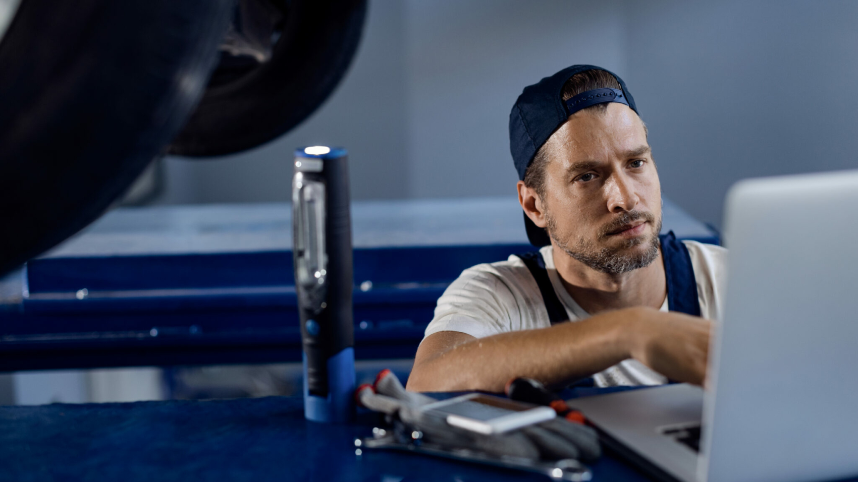 Auto repairman using computer while working in a workshop.